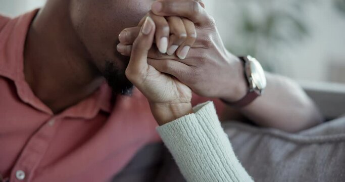 Love, kiss and hands of couple relax on a couch together for comfort and romantic bonding in a home or house. Support, African and calm people in a relationship cuddle with trust and affection