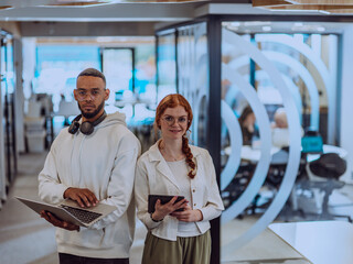 In a modern office African American young businessman and his businesswoman colleague, with her striking orange hair, engage in collaborative problem-solving sessions