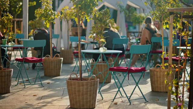View of the Eminescu square in Chisinau downtown at sunset, Moldova. Multiple chairs and tables near a cafe, decorations and greenery