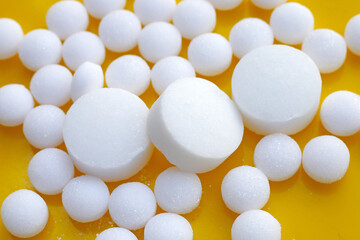 White mothballs on yellow background.