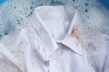 Dirty choclate stain on white shirt soaking in water with detergent water dissolution, washing cloth