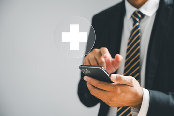 Mobile phone in hand displays plus icon, signifying positive value. Health insurance, benefits,...