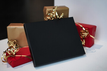 black voucher gift box as mockup template with red christmas presents or gifts around for black friday offers on white background
