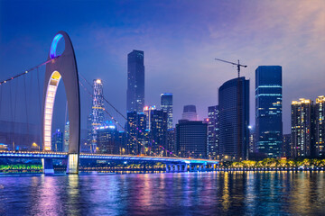 Guangzhou cityscape skyline over the Pearl River with Liede Bridge illuminated in the evening. Guangzhou, China - 679435298