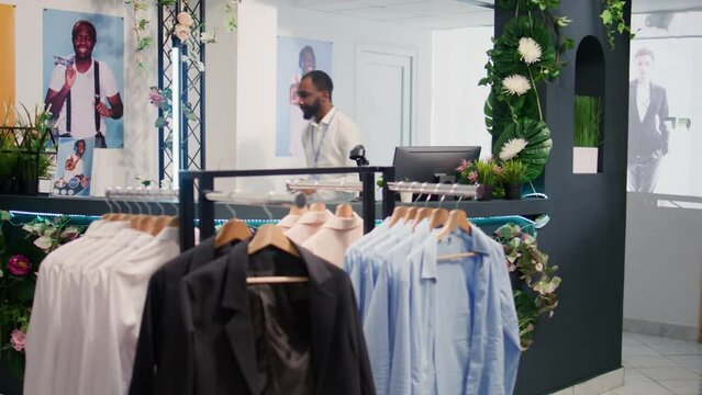 Retail assistant in stylish fashion boutique waiting to receive batch of new merchandise, imputing data on digital device. Worker in clothing store awaiting delivery of garments from new collection