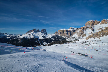 View of a ski resort piste with people skiing in Dolomites in Italy. Ski area Belvedere. Canazei,...