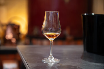 Tasting of cognac spirit aged in old French oak barrels in cellar in distillery in Cognac white...