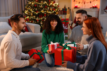 Christmas celebration. Happy friends exchanging gifts at home