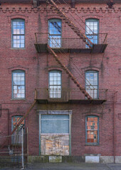 facade view of old factory building with red brick wall and fire ladder