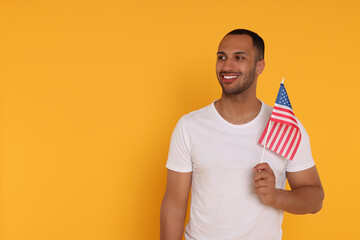 4th of July - Independence Day of USA. Happy man with American flag on yellow background, space for...