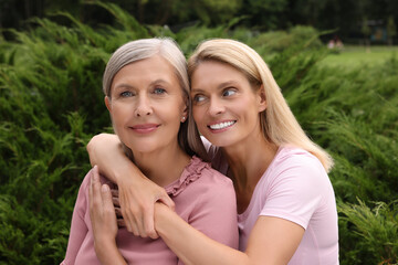 Happy mature mother and her daughter hugging outdoors