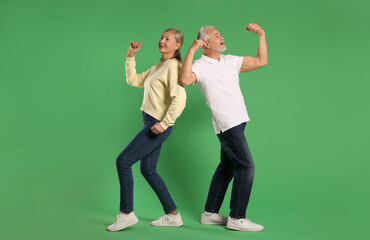 Senior couple dancing together on green background