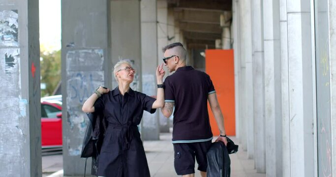 Couple strolls through the city. Active communication suggests dynamic interaction with urban surroundings, embracing punk spirit of freedom, self-expression, and defiant stance against societal norms