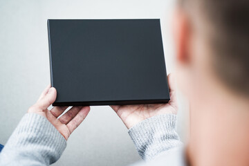 top view of an black voucher gift box as mockup for black friday offers holding with hands of a man