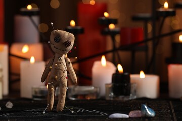 Voodoo doll pierced with pins on table in dark room, space for text. Curse ceremony
