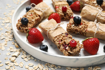 Tasty granola bars and ingredients on light table, closeup