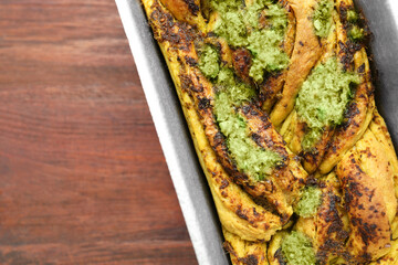 Freshly baked pesto bread in loaf pan on wooden table, top view. Space for text