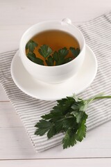 Aromatic herbal tea and fresh parsley on white wooden table