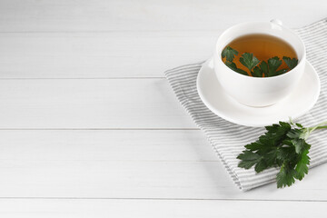 Aromatic herbal tea and fresh parsley on white wooden table, space for text