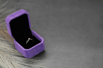 Jewelry box with stylish ring and feather on grey table. Space for text