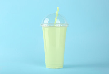 Plastic cup of tasty smoothie on light blue background