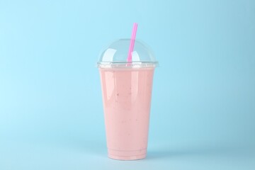Plastic cup of tasty smoothie on light blue background