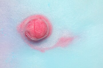 Pink bath bomb dissolving in water. Space for text
