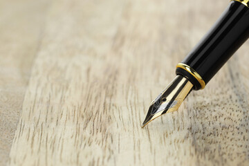 Stylish fountain pen on wooden table, closeup. Space for text