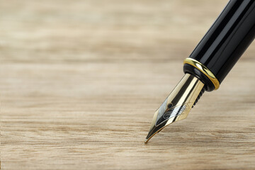 Stylish fountain pen on wooden table, closeup. Space for text