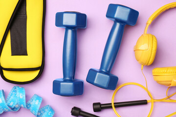 Flat lay composition with dumbbells on violet background