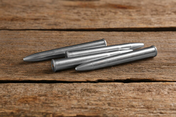 Many metal bullets on wooden table, closeup