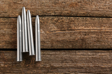 Metal bullets on wooden table, flat lay. Space for text