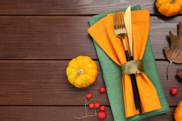 Cutlery, napkins and autumn decoration on wooden background, flat lay with space for text. Table...