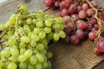 Different fresh ripe grapes on wooden table, closeup