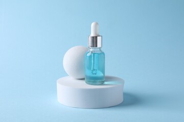 Presentation of bottle with cosmetic serum on light blue background