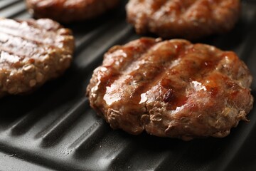 Delicious hamburger patties cooking on electric grill, closeup