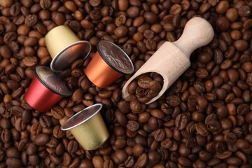 Many different coffee capsules and scoop on beans, top view