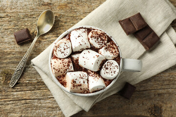 Delicious hot chocolate with marshmallows, cocoa powder and pieces on wooden table, flat lay