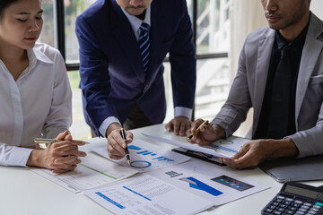 Happy young female financial advisor talking with clients and showing investment reports to clients at office table, showing data, budget charts or legal results.