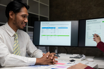Happy young female financial advisor talking with clients and showing investment reports to clients at office table, showing data, budget charts or legal results.