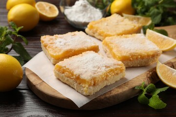 Tasty lemon bars with powdered sugar and mint on wooden table, closeup