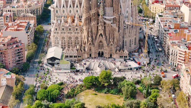 Aerial drone view of Sagrada Familia in city downtown. People and residential districts around, greenery, Barcelona, Spain