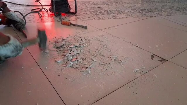 Construction workers demolish damaged ceramic floors that will be replaced 