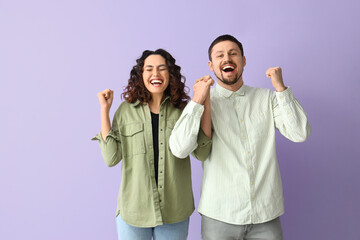 Happy young couple holding hands on lilac background