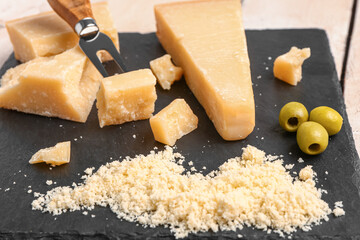 Board with pieces of tasty Parmesan cheese on table, closeup
