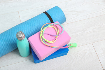 Yoga mat, blocks, bottle of water and skipping rope on floor in gym