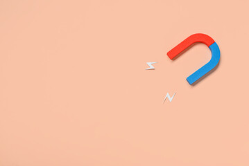 Horseshoe shaped magnet with paper lightnings on beige background