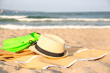 Towel with hat, bag and flippers on sand