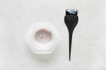 Bowl with hair dye and brush on white background