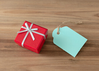 Red close gift box with a blue tag isolate on wood background.
